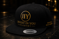 Invest In You Academy snapback hat side view — navy blue adjustable cap with gold logo